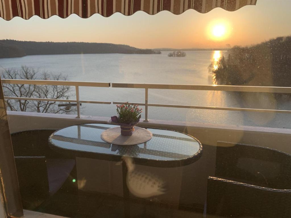 a table on a balcony with a view of the water at Appartement Seesicht in Malente