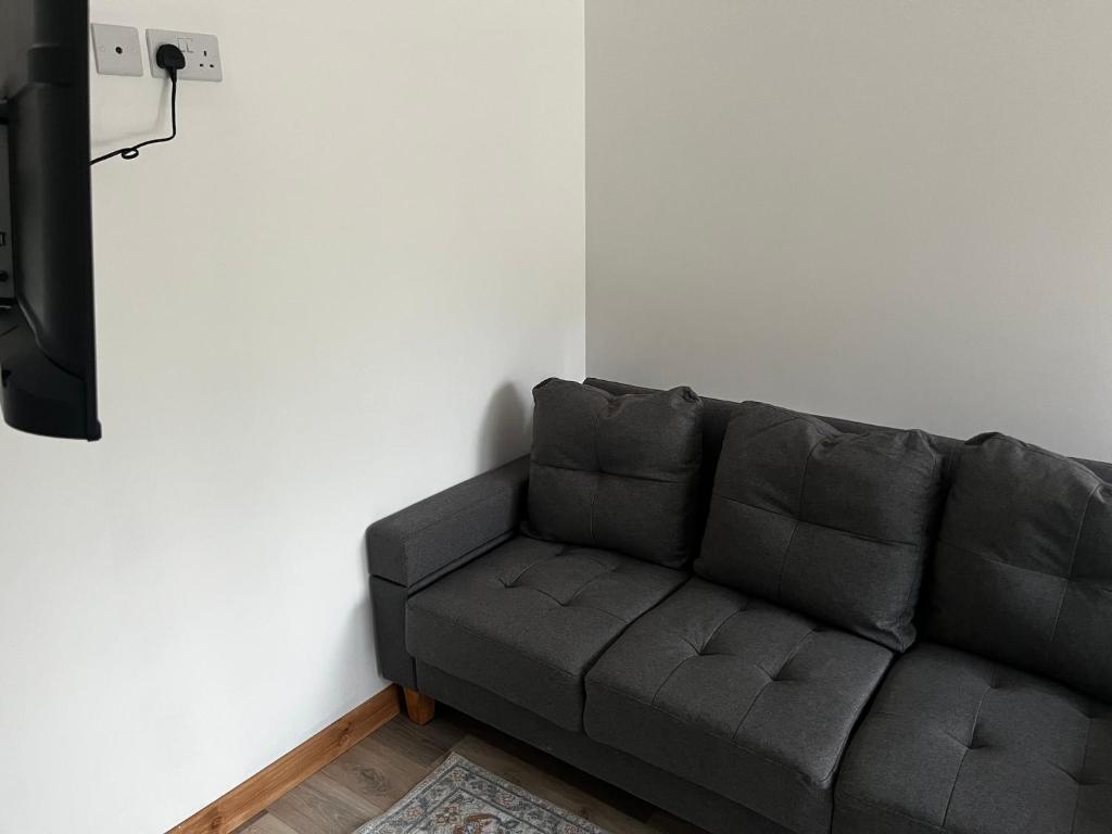 a gray couch sitting in a room next to a wall at Small home in Llanfairpwll in Llanfairpwllgwyngyll