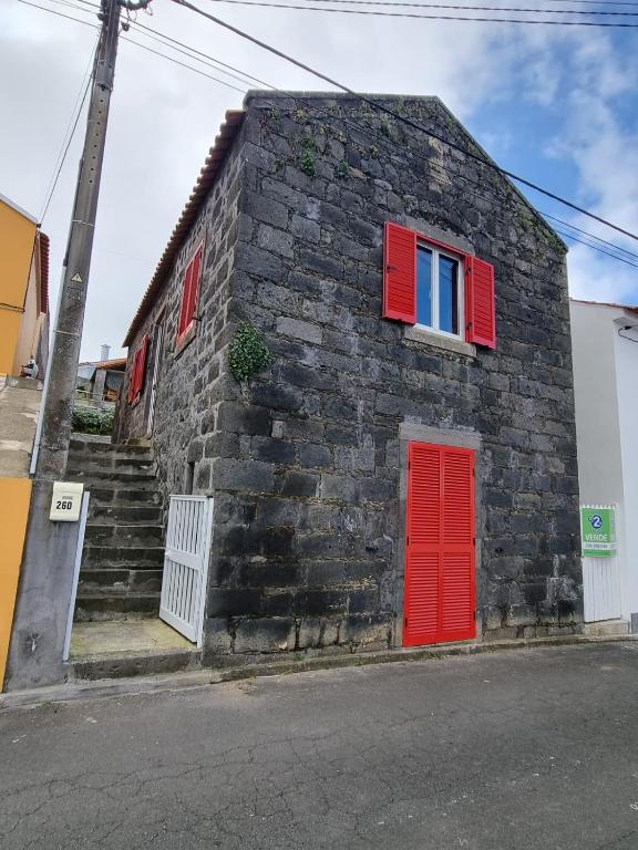 a brick building with red doors and red windows at Casa C'alma in Ponta Delgada
