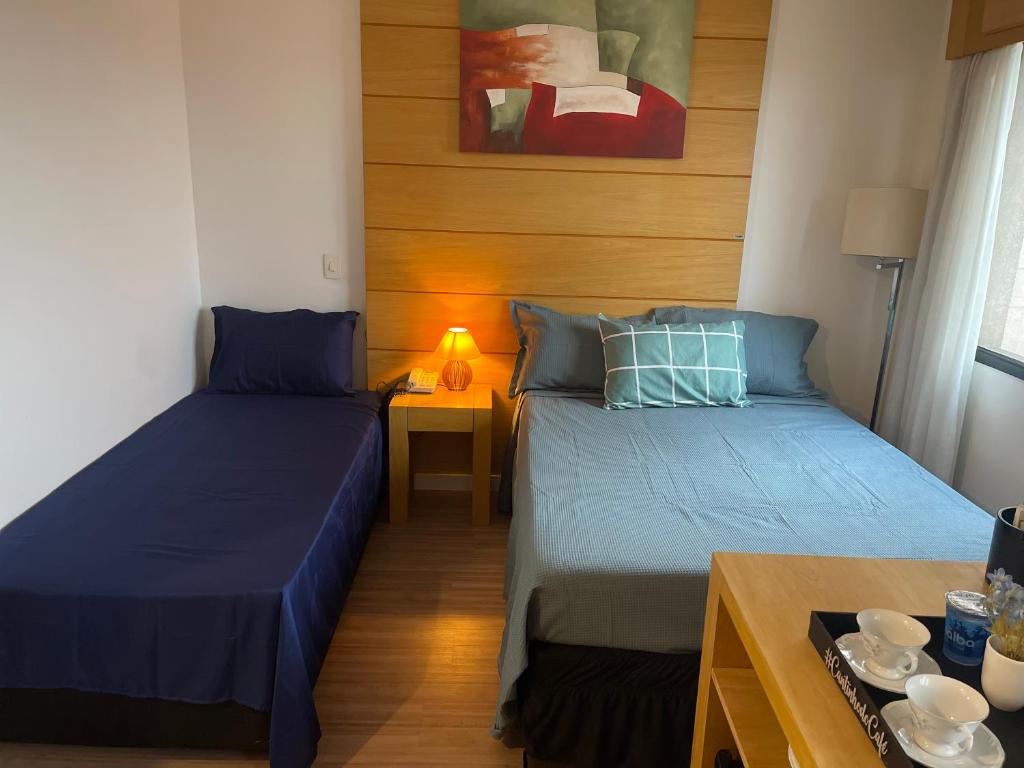 Habitación pequeña con 2 camas y mesa. en Flat de Luxo Aeroporto Congonhas - Hotel eSuites, en São Paulo