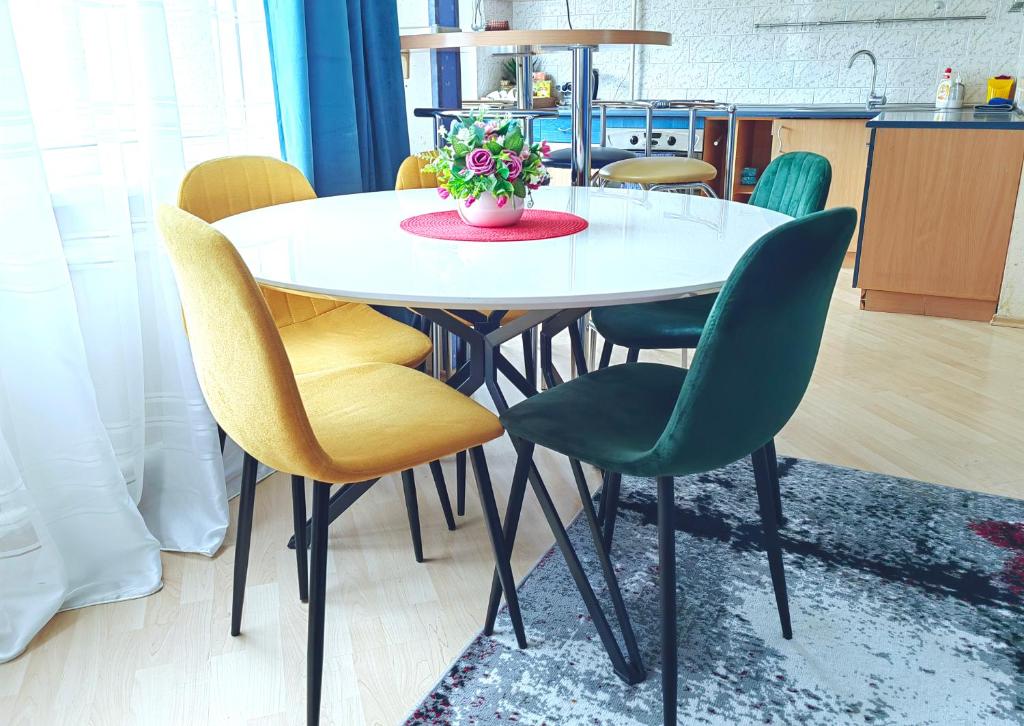 a table with chairs and a vase of flowers on it at EMVIKA apartament in Šiauliai