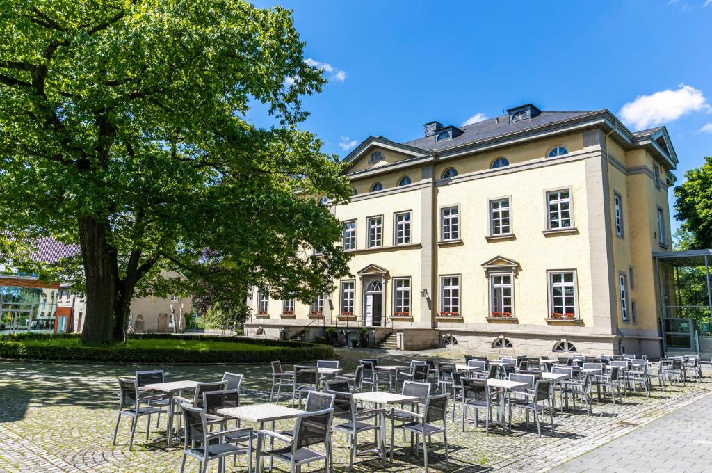 un gruppo di tavoli e sedie di fronte a un edificio di Haus Villigst - Tagungsstätte der EKvW a Schwerte