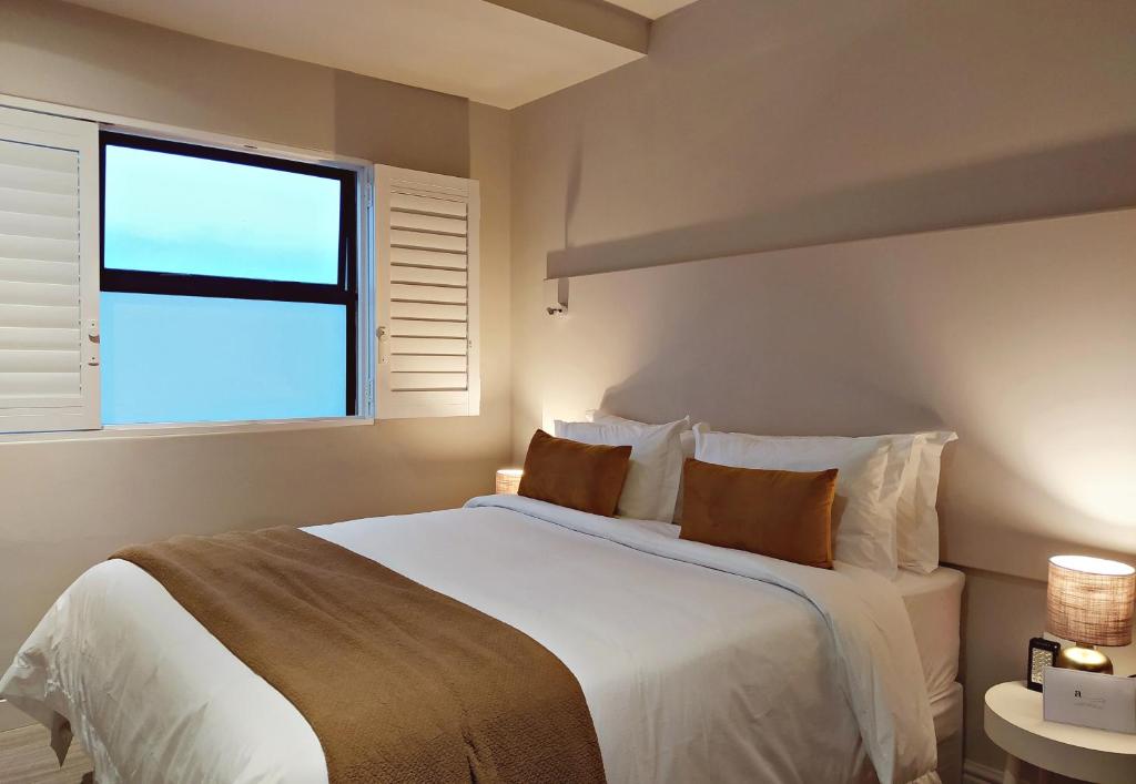 a bedroom with a large white bed with a window at Apartment at Hermanus Waterfront in Hermanus