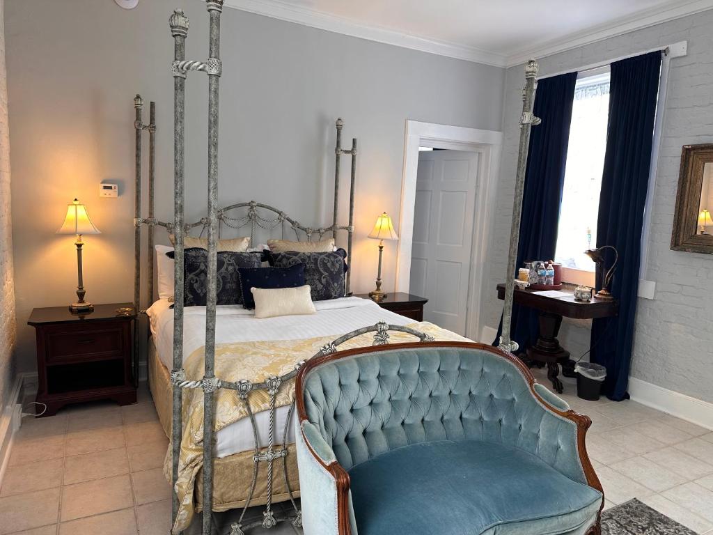 a bedroom with a canopy bed and a blue chair at The Inn at Cedar Grove in Vicksburg