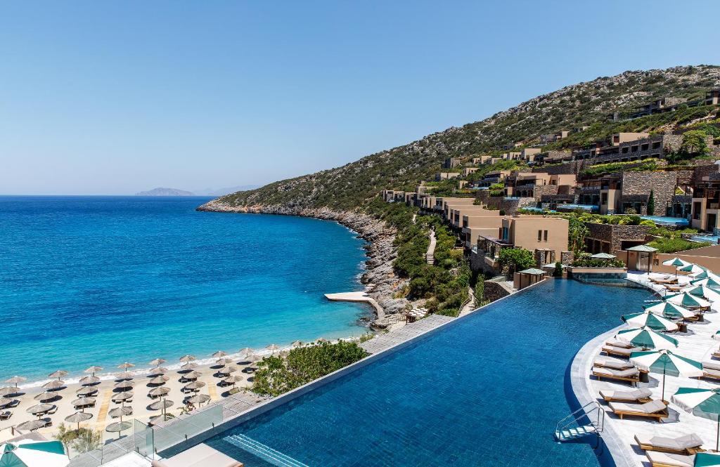 uma vista para um resort com guarda-sóis e para o oceano em Daios Cove em Agios Nikolaos