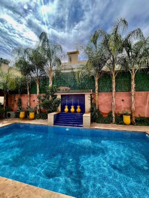una piscina frente a un edificio con palmeras en Villa HANIA - Ensoleillée et sans vis-à-vis, en Marrakech