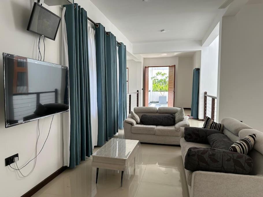 sala de estar con 2 sofás y TV de pantalla plana en Beauty World Villa - Gampaha en Gampaha