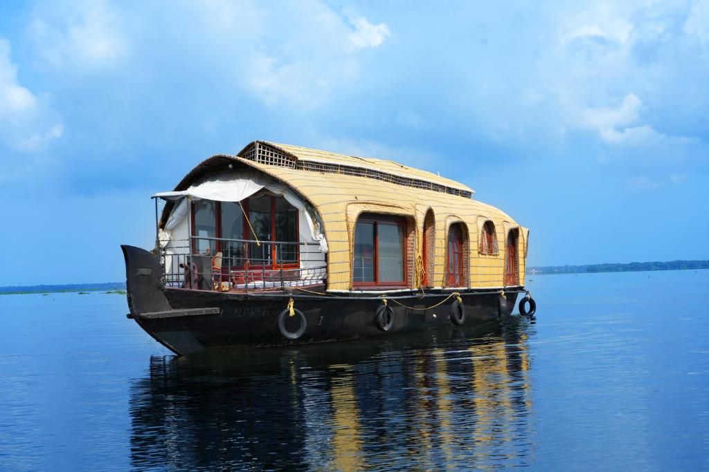 una barca di legno seduta sull'acqua di Aqua Castle Houseboat - by Aqua Jumbo Houseboats a Alleppey