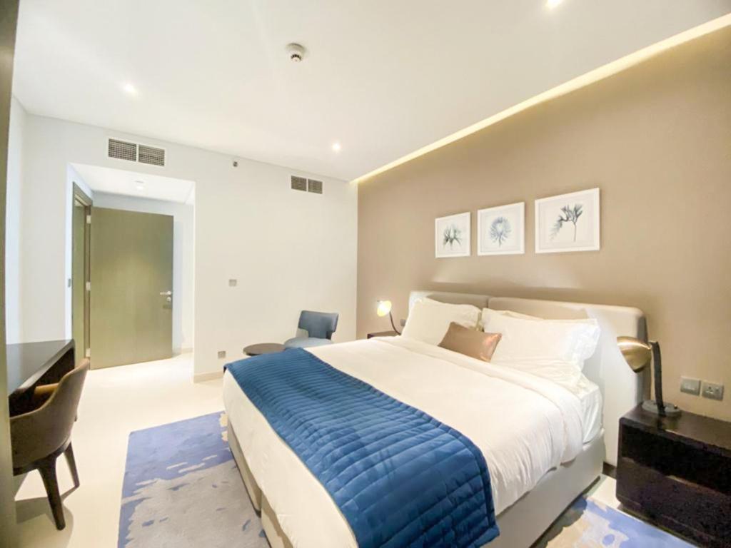 a bedroom with a large bed and a desk at Comfy 1BR in Damac Maison Prive by Huaxia Homes in Dubai