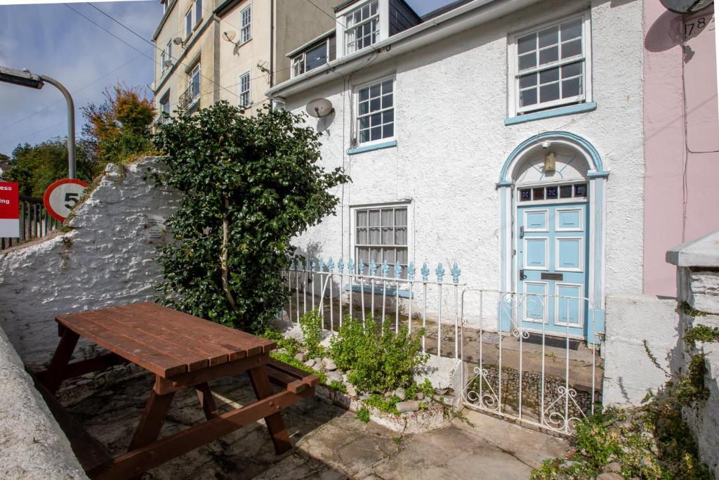 a wooden bench in front of a white house at Cottage in the Heart of Brixham in Brixham