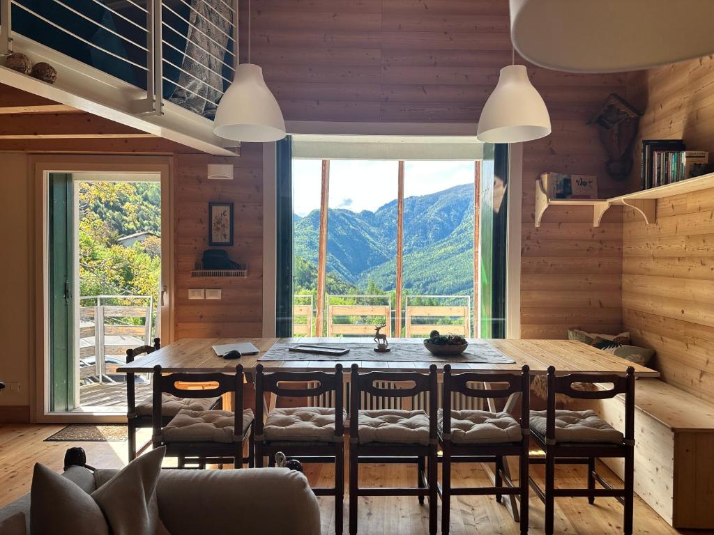 uma sala de jantar com mesa e cadeiras e uma grande janela em CIELO E TERRA Chalet a Zencheri em Piazza