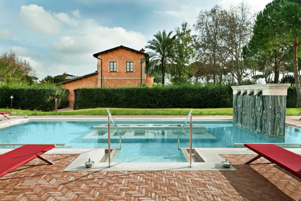 una piscina con 2 sillas rojas y una casa en QC Termeroma Spa and Resort, en Fiumicino