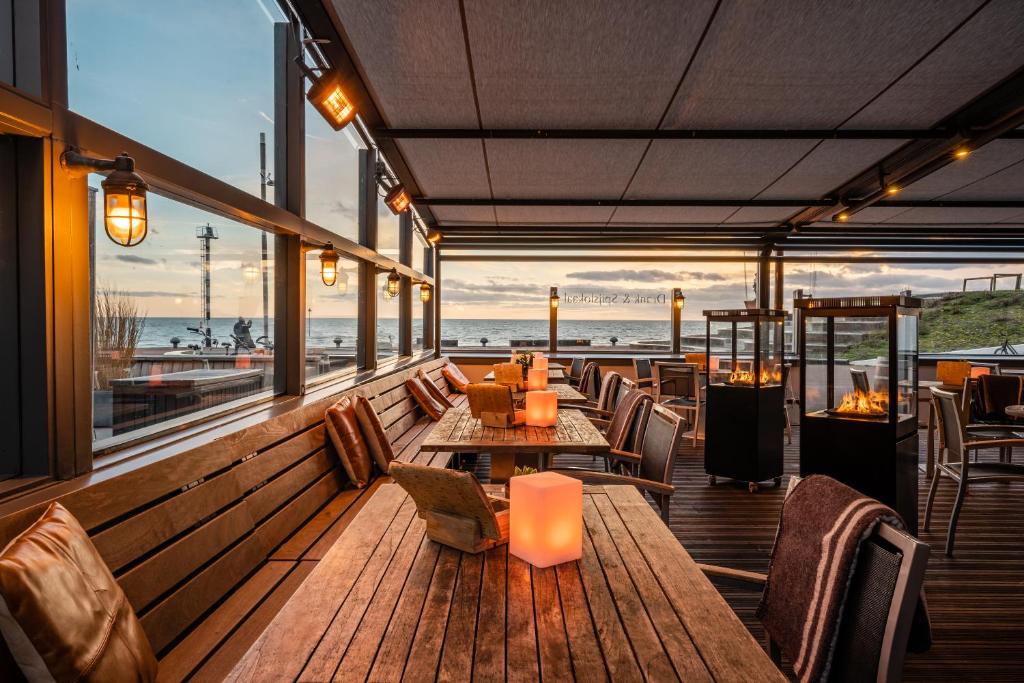 un restaurante con mesas y sillas y vistas al océano en Stuifdijk en Oost-Vlieland