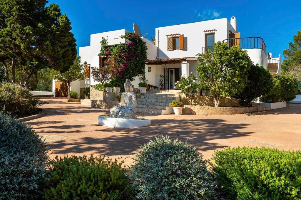 una casa blanca con una estatua delante de ella en Casa Aalaya: Ibiza Mediterranean Retreat, en Illes Balears