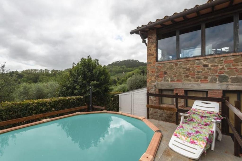 a swimming pool with two chairs and a house at Il Piccolo Eden in Pescia
