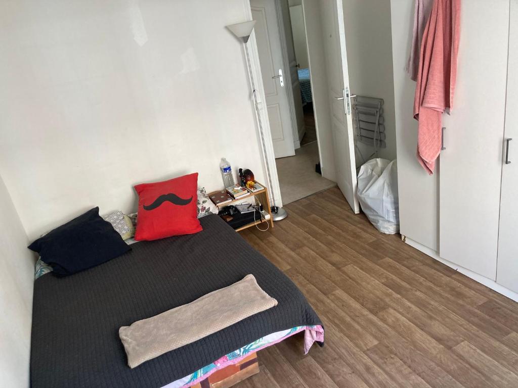 une chambre avec un lit avec des oreillers rouges et noirs dans l'établissement Paris12, à Paris