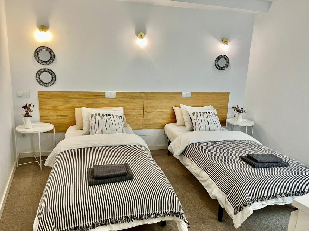 two beds in a room with clocks on the wall at Hola Hostel Alicante in Alicante