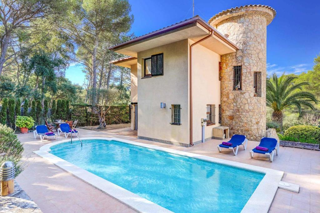 una piscina frente a una casa con sillas azules en La Torreta, en Palafrugell