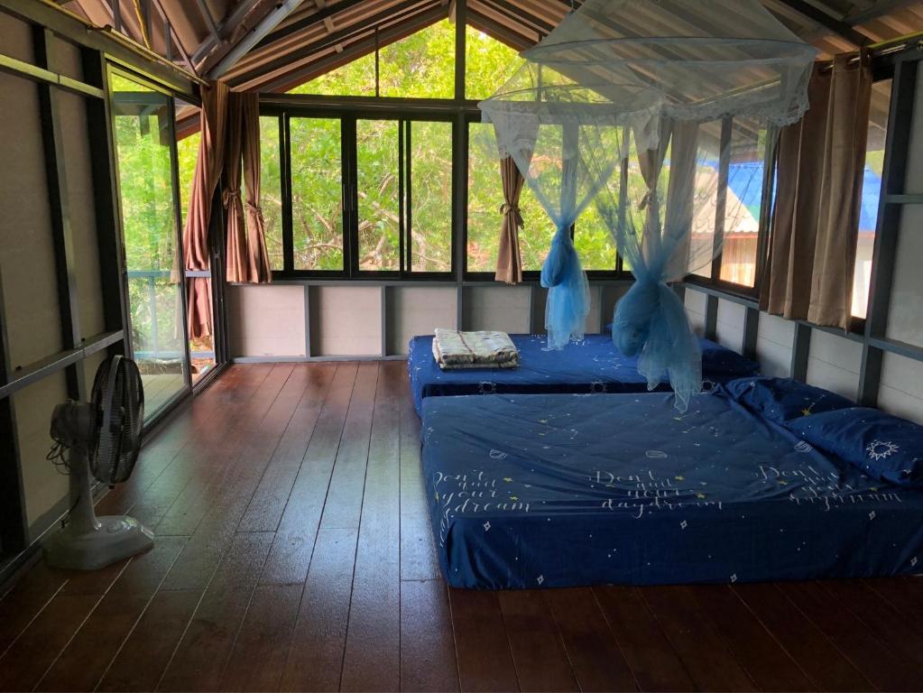 1 dormitorio con 1 cama azul en una habitación con ventanas en The Big House, en Koh Chang