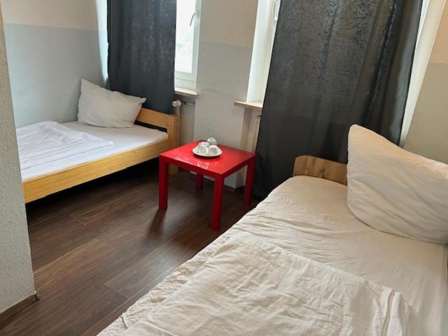 a small room with two beds and a red table at Pension Nürnberg in Nürnberg