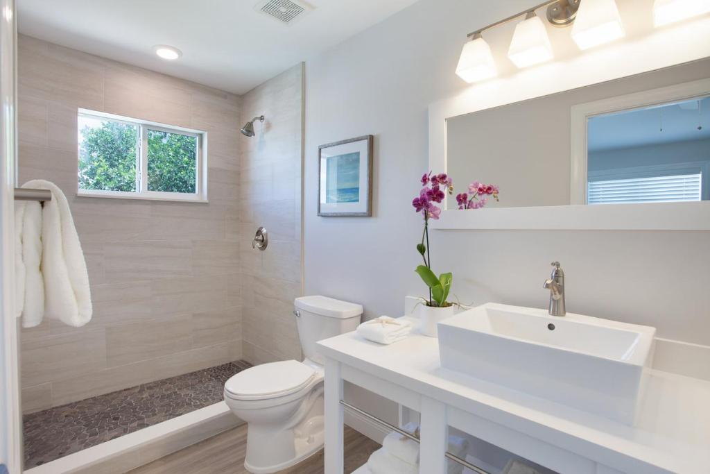 a white bathroom with a toilet and a sink at Isla Tamarillo - Waterfront Boutique Resort, Island Paradise, Prime Location in Islamorada