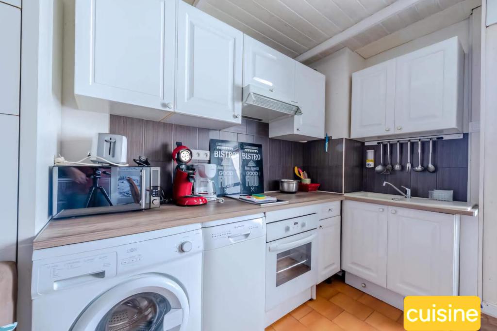 cocina con armarios blancos, lavadora y secadora en Grand studio à 150m de la plage et 200m du port !, en Saint-Cyprien