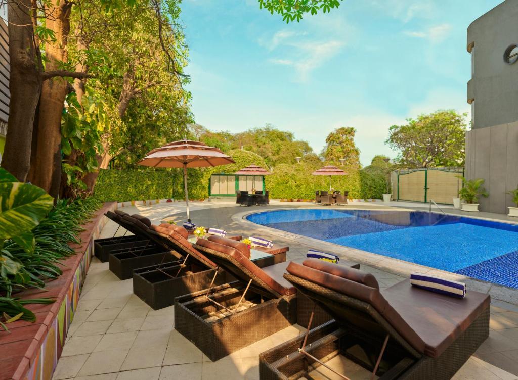 a swimming pool with chairs and an umbrella next to a pool at Vivanta Vadodara in Vadodara