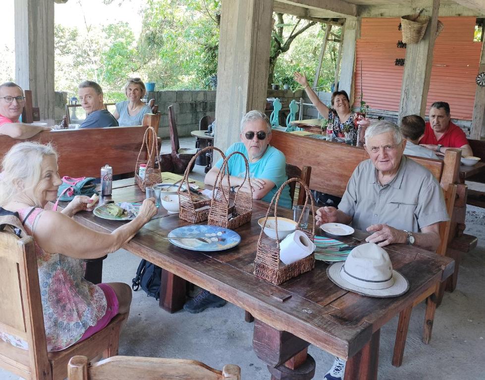 een groep mensen die rond een houten tafel zitten bij Batad Pension and Restaurant in Banaue