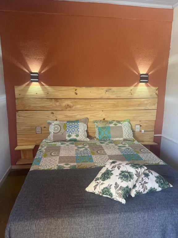 a bedroom with a bed with a wooden headboard and pillows at Pousada Recanto do Tucano in Cavalcante