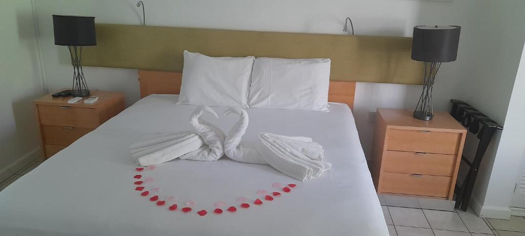 ein Bett mit weißen Decken und Kissen darauf in der Unterkunft Ocean's Edge Lodge Restaurant & Bar in Roseau