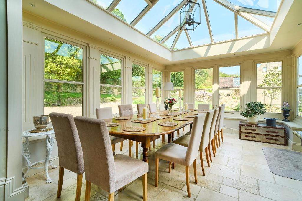a conservatory dining room with a wooden table and chairs at Berkeley House near Bath in Bath