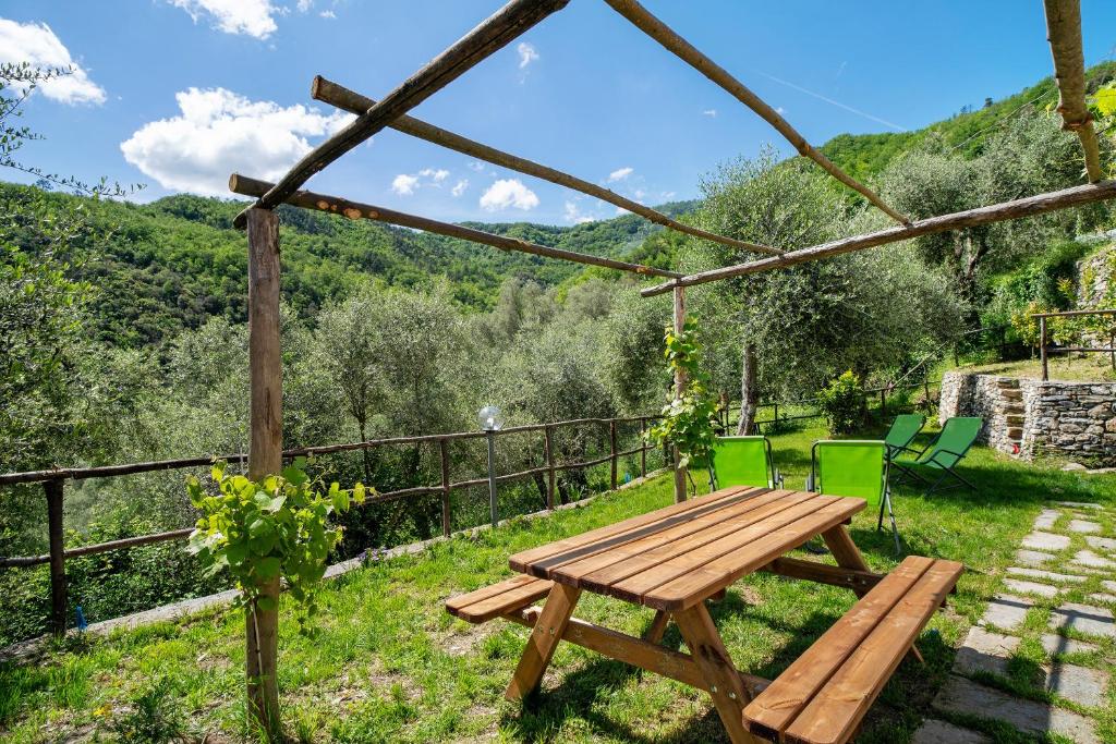 uma mesa de piquenique em madeira e cadeiras num jardim em La casa di Bosco em Casanova Lerrore