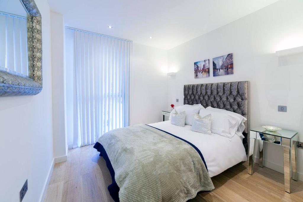 a white bedroom with a large bed with white pillows at Exclusive Tower Bridge Apartment in London