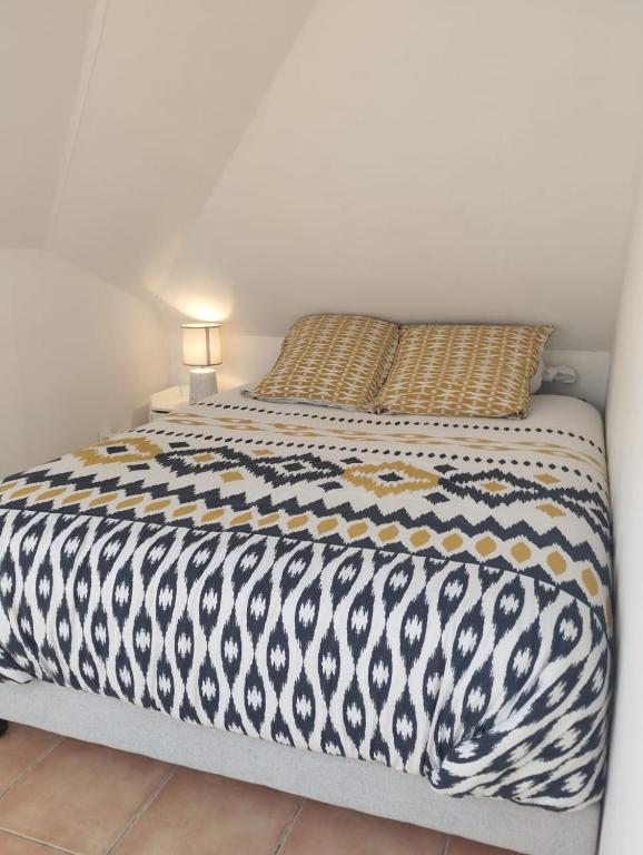 a bed with a black and white comforter on it at CASA COLIVING avec chambre salle de bain individuelles privatives in Saint-Pierre