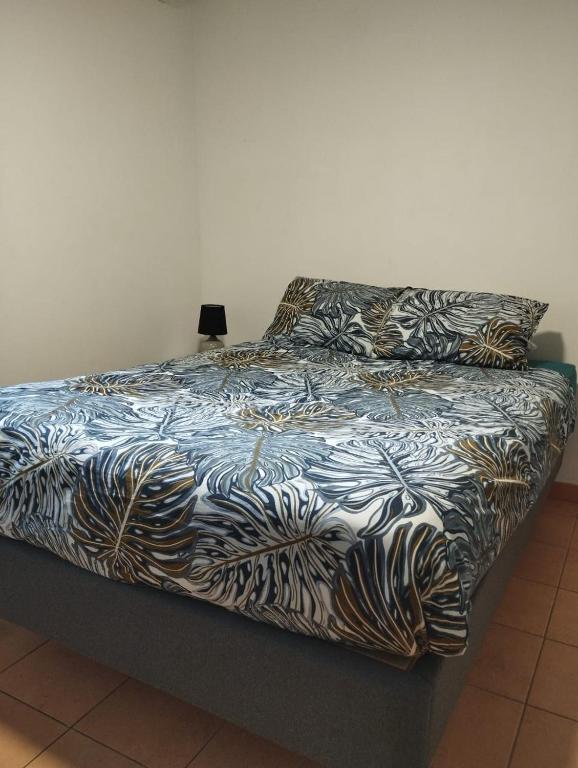 a bed with a black and white comforter on it at CASA COLIVING avec chambre salle de bain individuelles privatives in Saint-Pierre