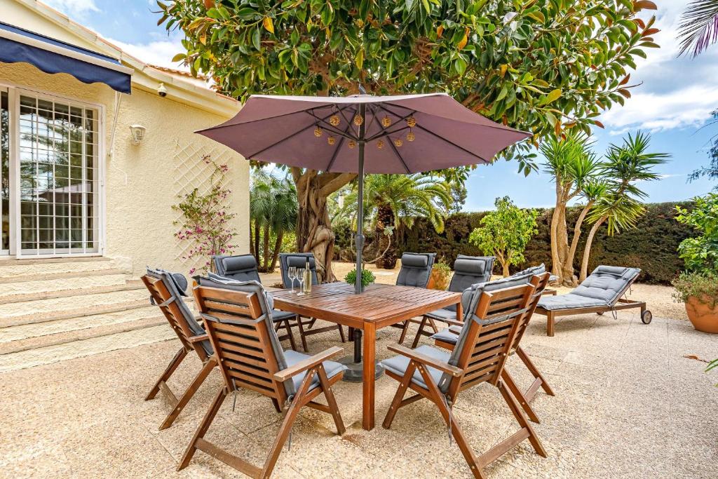 a wooden table with chairs and an umbrella at Villa Los Pinos 6 in Altea