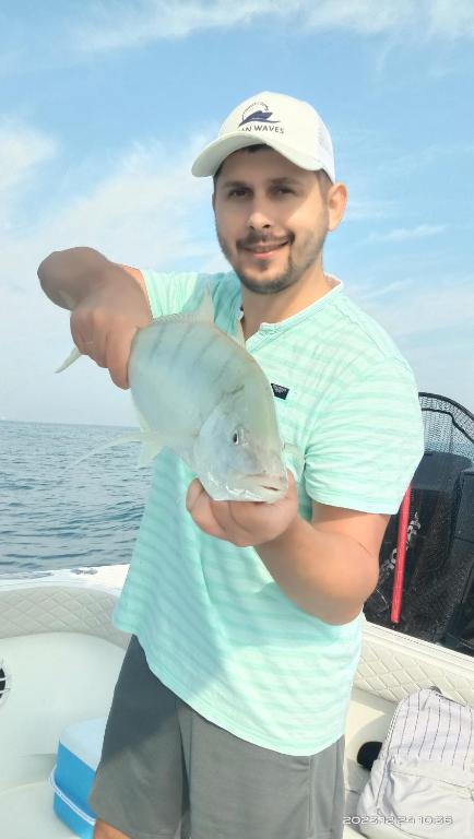 un hombre sosteniendo un pez en un barco en Dubai fishing trip 5 hours, en Dubái