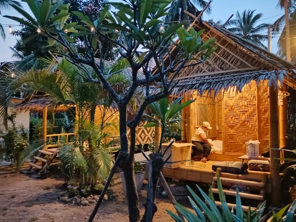 a man sitting on the porch of a house at Bamboo homestay at samroiyot in Baanphakrimlay 