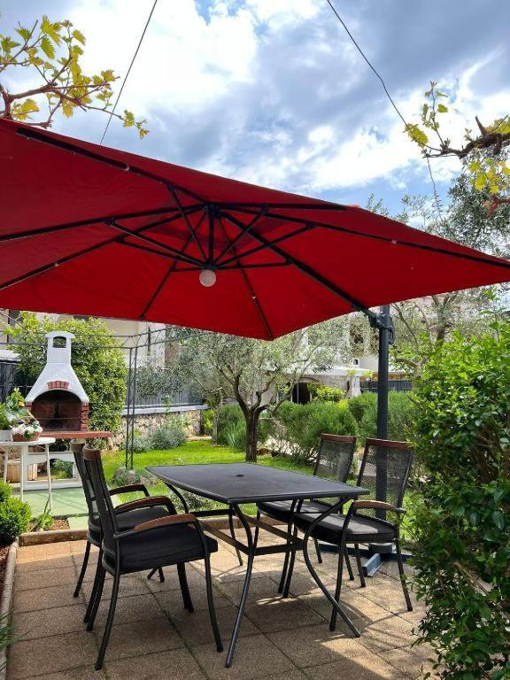 a table and chairs under a red umbrella at Bernarda in Skrbčići