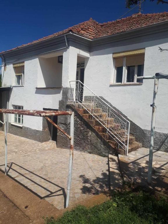 une maison blanche avec un escalier en face de celle-ci dans l'établissement HOLIDAY HOME - NEGREVO, à Pehčevo