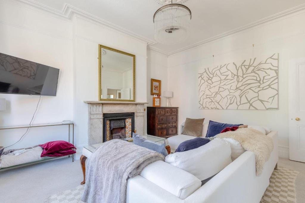 een woonkamer met een witte bank en een open haard bij Elegant 1BD Victorian Flat Hampstead Heath! in Londen