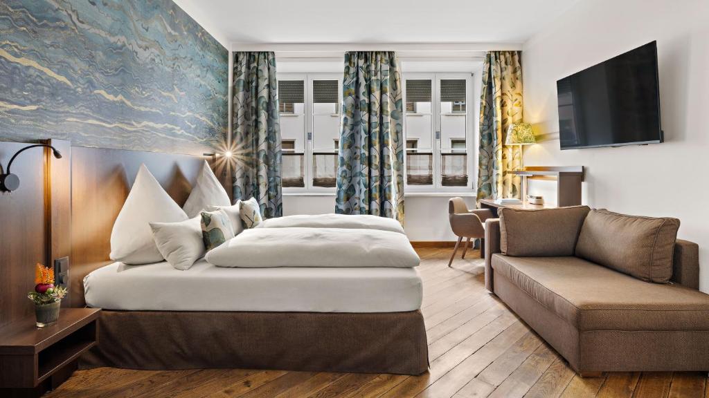 a hotel room with a bed and a couch at Hotel Deutsche Eiche in Munich