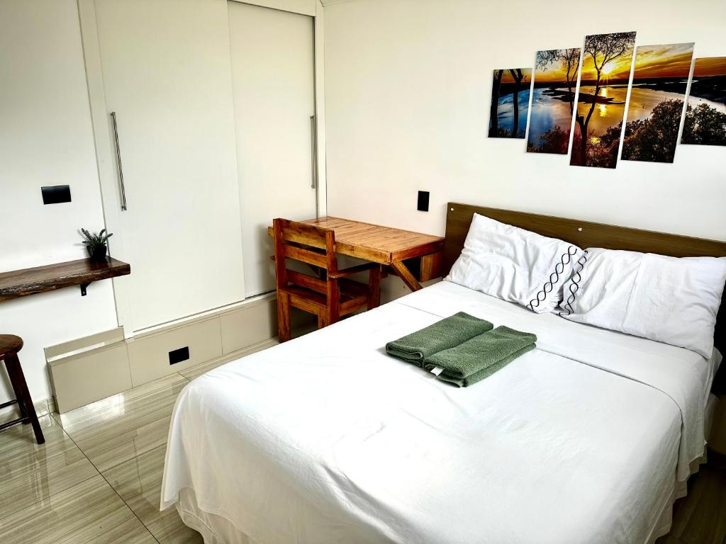 um quarto com uma cama branca e uma secretária em LOFT IGUASSU FALLS *GARAGEM* em Foz do Iguaçu