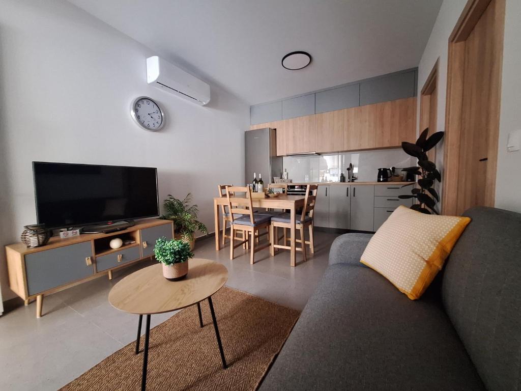 ein Wohnzimmer mit einem Sofa und einem Tisch sowie eine Küche in der Unterkunft modern apt near Heraklion city & airport in Néa Alikarnassós