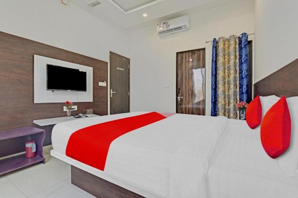 1 dormitorio con 1 cama blanca grande con almohadas rojas en Hotel ANGAN, en Udaipur