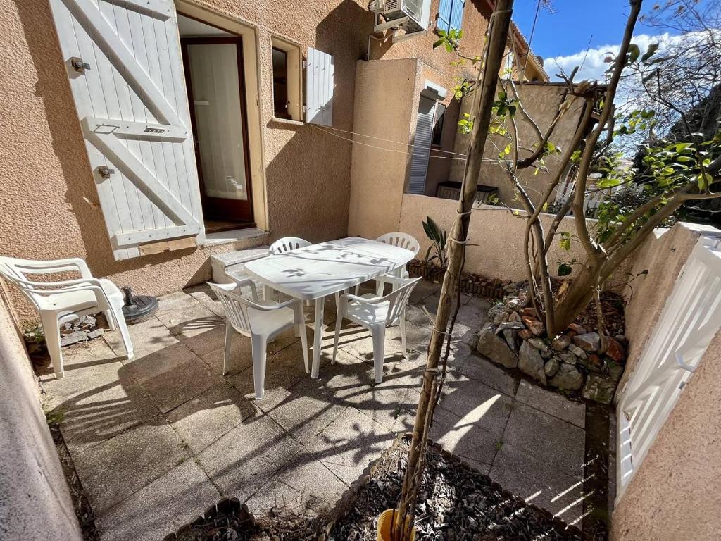 une table blanche et des chaises assises sur une terrasse dans l'établissement Jolie maison T3 proche du centre Narbonne plage, à Narbonne-Plage