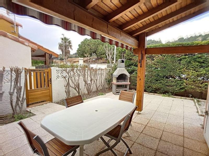 un tavolo bianco e sedie su un patio con griglia di Pavillon T2 avec grande terrasse a Narbonne-Plage