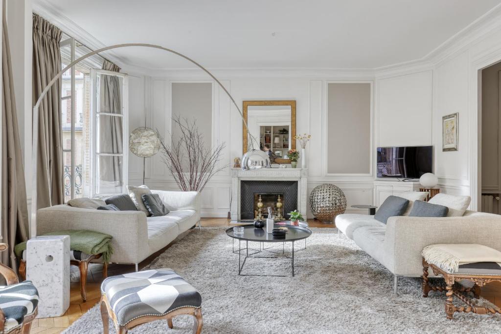 Elle comprend un salon doté d'un mobilier blanc et d'une cheminée. dans l'établissement Wonderful & large flat in the 7th - Eiffel Tower, à Paris