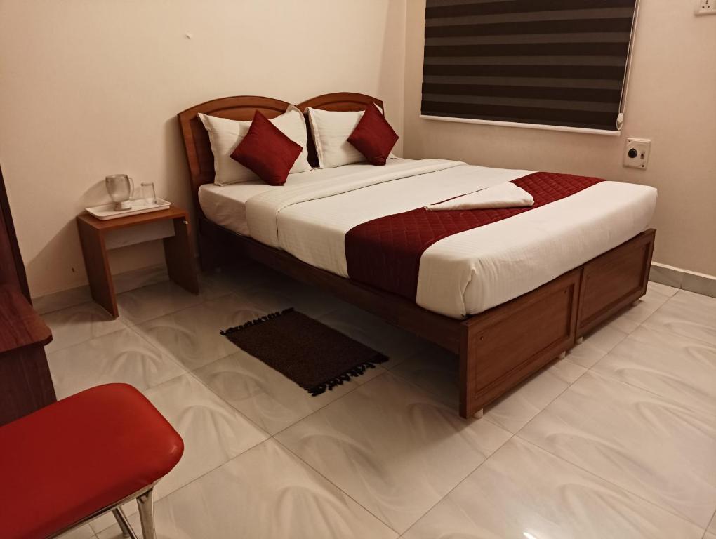 a bedroom with a large bed with a red chair at Rooms in Chennai