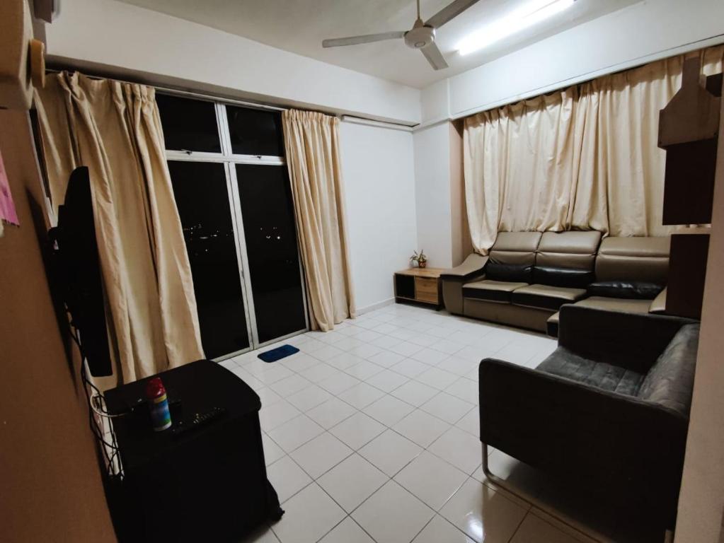 a living room with a couch and a large window at FAMILY SWEET SUITE in Kota Bharu